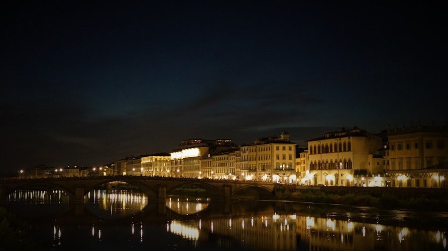 Nocna panorama Florencji nad rzeką Arno z oświetlonym mostem Ponte Vecchio