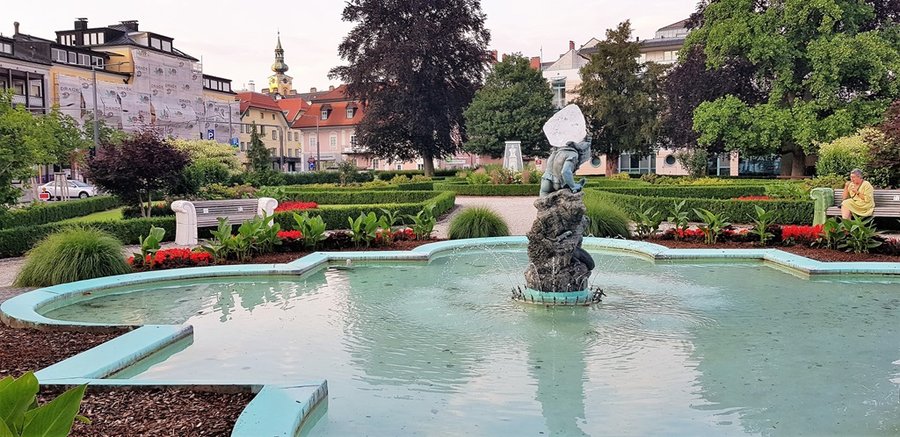 Fontanna w parku miejskim w Gmunden z rzeźbą i klombami kwiatów