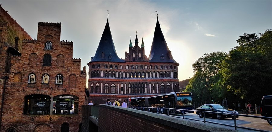 Holstentor widziany z mostu nad kanałem, z przejeżdżającym autobusem i ruchem ulicznym