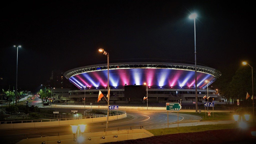 Podświetlona hala widowiskowo-sportowa Spodek w Katowicach nocą