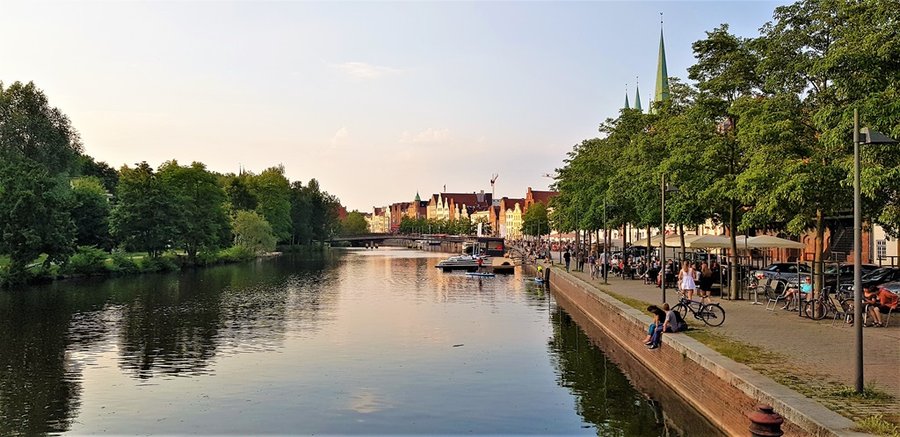 Kanał w Lubece z łodziami i nadbrzeżną promenadą pełną spacerowiczów
