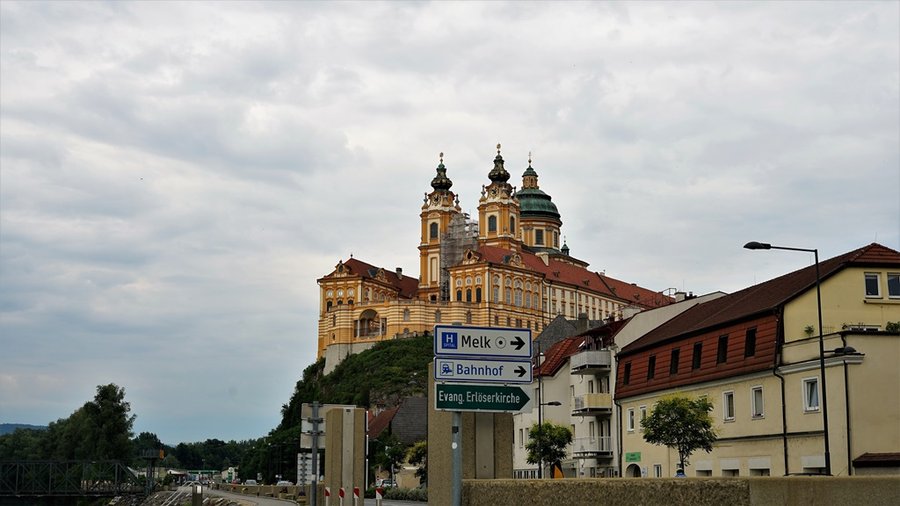 Opactwo w Melk widziane znad Dunaju, z tablicami kierunkowymi Melk i Bahnhof