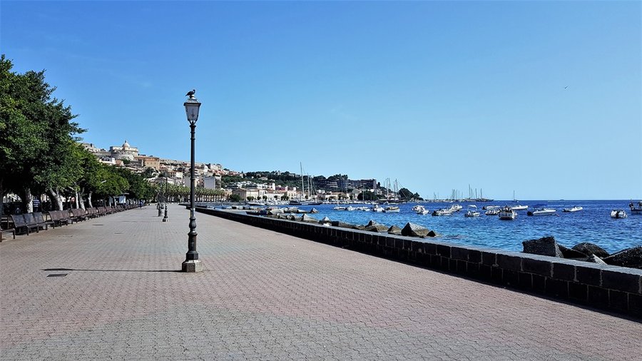 Promenada w Milazzo z latarnią i widokiem na starą część miasta oraz port jachtowy