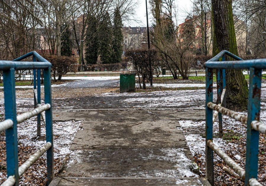 Niebieska metalowa barierka na alejce w zaśnieżonym Parku Dubiela w Zabrzu