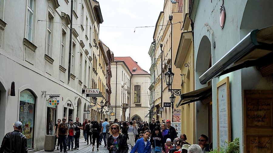Ulica Celetná w Pradze pełna turystów, prowadząca w stronę Bramy Prochowej