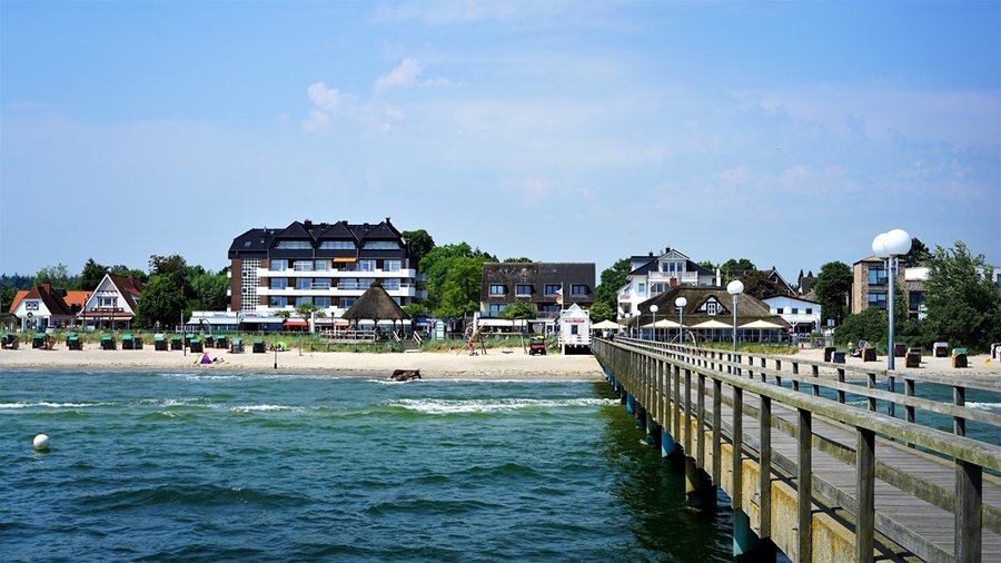 Drewniane molo w Scharbeutz nad Morzem Bałtyckim z zabudową nadmorską w tle