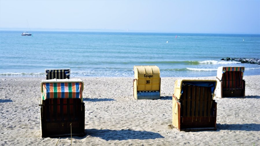 Drewniany plac zabaw w kształcie żaglowca na piaszczystej plaży w Timmendorfer Strand, w tle morze i molo