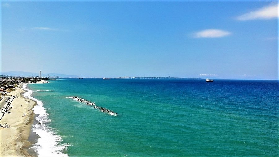 Widok z drona na plażę Venetico z falami przyboju, w tle widoczne statki na morzu
