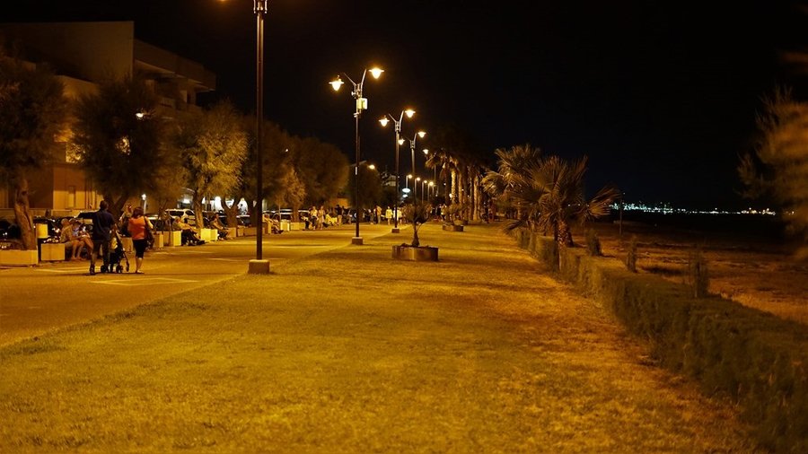 Nocna promenada w Venetico udekorowana flagami i oświetleniem nad wodą