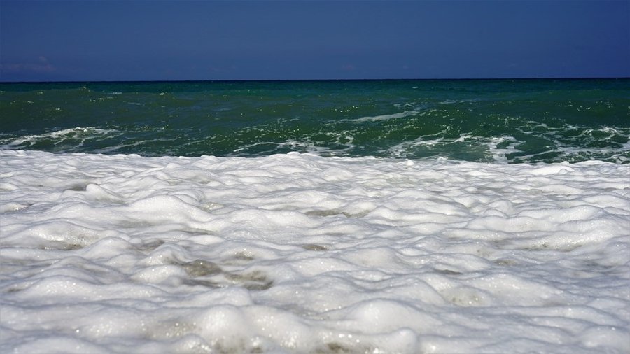 Zbliżenie na pianę morskich fal na plaży w Venetico