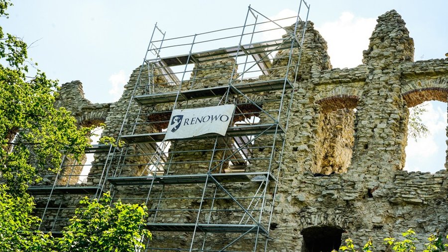 Prace renowacyjne na murach ruin Zamku Rabsztyn, rusztowanie z banerem firmy Renowo