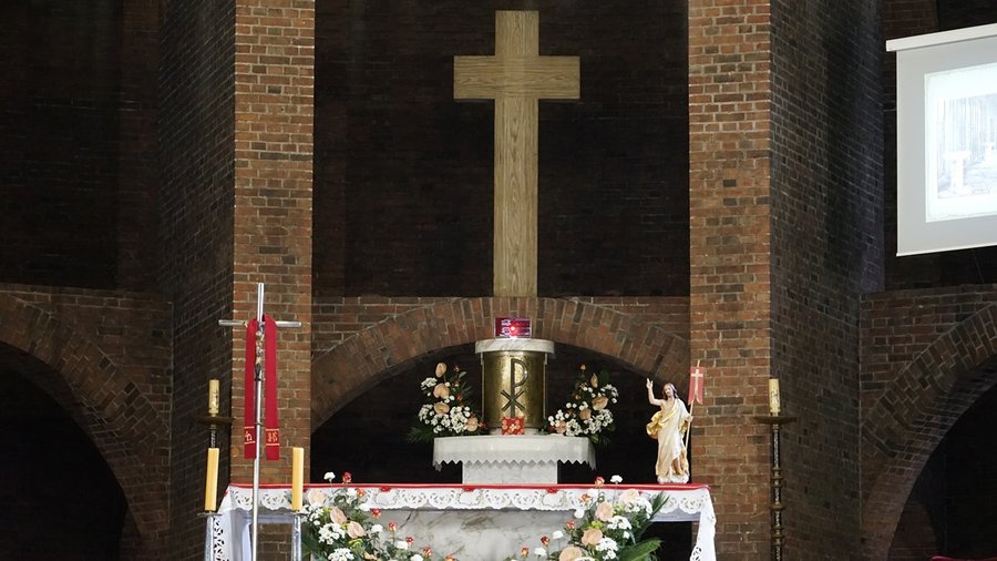 Prosty drewniany krzyż na murze z cegły we wnętrzu kościoła św. Józefa w Zabrzu